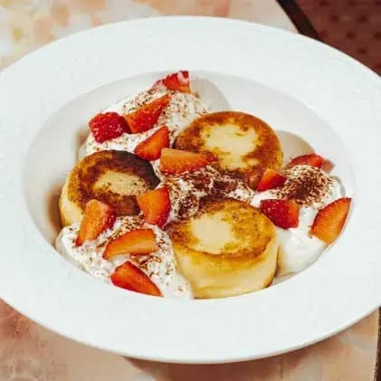 breakfast/20260609111937-sirniki-with-cream-fresh-berries-and-berry-confiture.webp